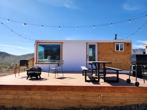 A wooden deck with a barbecue grill, a table, and chairs.