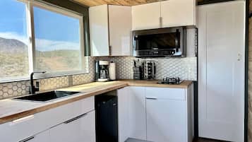 A kitchen with white cabinets, a microwave, a sink, and a dishwasher.