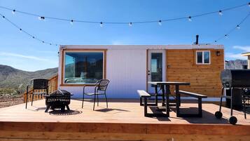 A wooden deck with a barbecue grill, a table, and chairs.