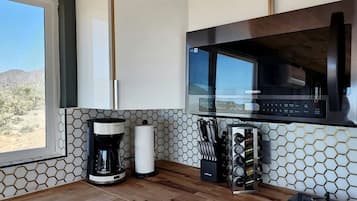 A modern kitchen with a built-in microwave, coffee maker, and gas stove.