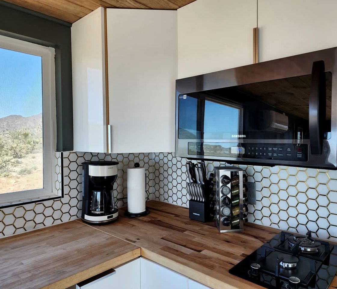 A modern kitchen with a built-in microwave, coffee maker, and gas stove.