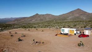 A desert landscape with a mobile home, a red car, and a small shed. - Stunning Tiny House with Picnic Space, Barbecue and Fire Pit in Meadview, Arizona (Mohave Valley)