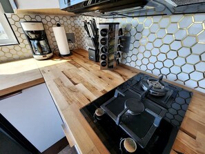 A compact kitchen with a built-in stove, a coffee maker, and a spice rack. - Stunning Tiny House with Picnic Space, Barbecue and Fire Pit in Meadview, Arizona (Mohave Valley)