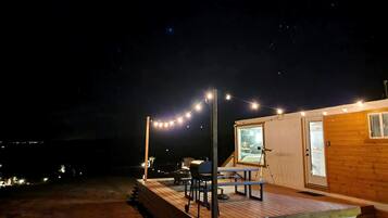 Eine Holzhütte mit einer Terrasse, Sitzgelegenheiten im Freien und einem Teleskop.