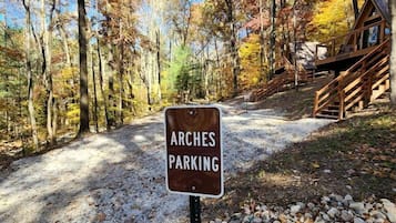 A sign indicating 'ARCHES PARKING' in a forested area with a cabin in the background.