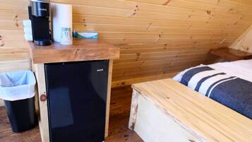 Pieni huone, jossa on pieni musta jääkaappi, kahvinkeitin ja roskakori.