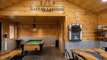 Una mesa de billar, una mesa de pool y un letrero que dice 'Tappan Lakeside Resort' en una sala de madera.