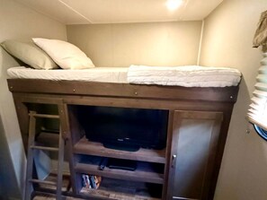 A bunk bed with a television in a wooden cabinet below.