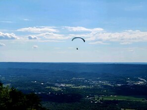 A person paragliding over a landscape with a clear sky.
