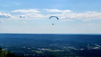 A person paragliding over a landscape with a clear sky.
