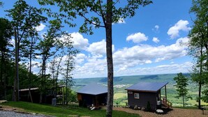 A cabin with a metal roof, surrounded by trees and a view of a valley. - Unique Container with BBQ Ideal for Couples in Georgia (Rising Fawn)