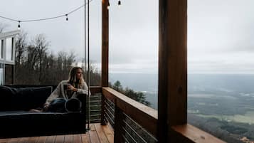 A person sitting on a wooden deck with a view of a landscape.