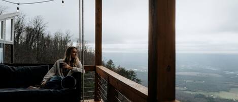 Una persona sentada en una terraza de madera con vistas al paisaje.