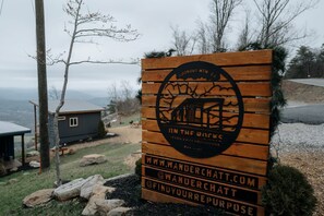 A wooden sign with a logo and text for a mountain retreat, including a website and social media handle. - Unique Container with BBQ Ideal for Couples in Georgia (Rising Fawn)