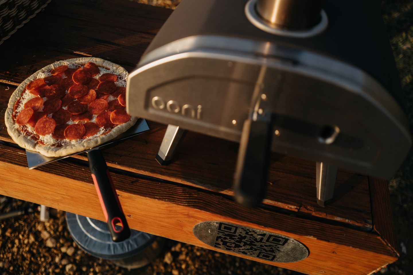 Una pizza sobre una mesa de madera, junto a un horno de pizza.