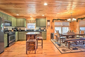 A log cabin interior with a kitchen, dining area, and a fireplace.