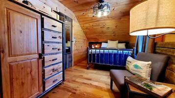 A wooden interior with a bed, a desk, and a wardrobe.