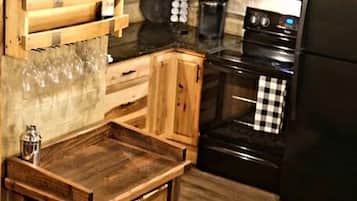 A kitchen with wooden cabinets, a black oven, a black refrigerator, and a hanging light fixture.