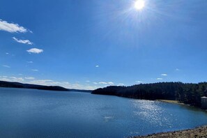 Un lac paisible, avec un ciel dégagé et des collines qui se dessinent à l’horizon.