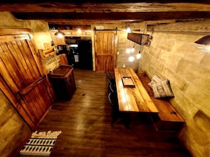 A rustic wooden interior with a dining table, benches, and a kitchen area.