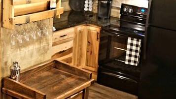 A kitchen with wooden cabinets, a black oven, a black refrigerator, and a hanging light fixture.