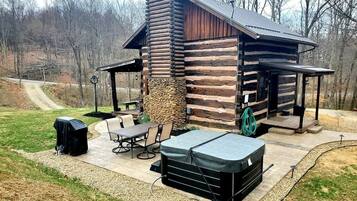 Une cabane en rondins avec une cheminée en pierre, un espace salon extérieur et un jacuzzi.