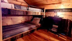 A wooden interior with bunk beds and a small table.
