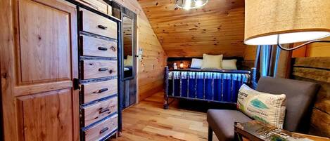 A wooden interior with a bed, a desk, and a wardrobe.