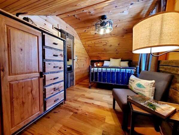 A wooden interior with a bed, a desk, and a wardrobe.