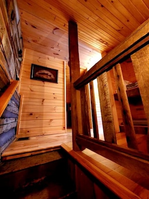Interior de madera con una escalera, paredes de madera y un cuadro en la pared.