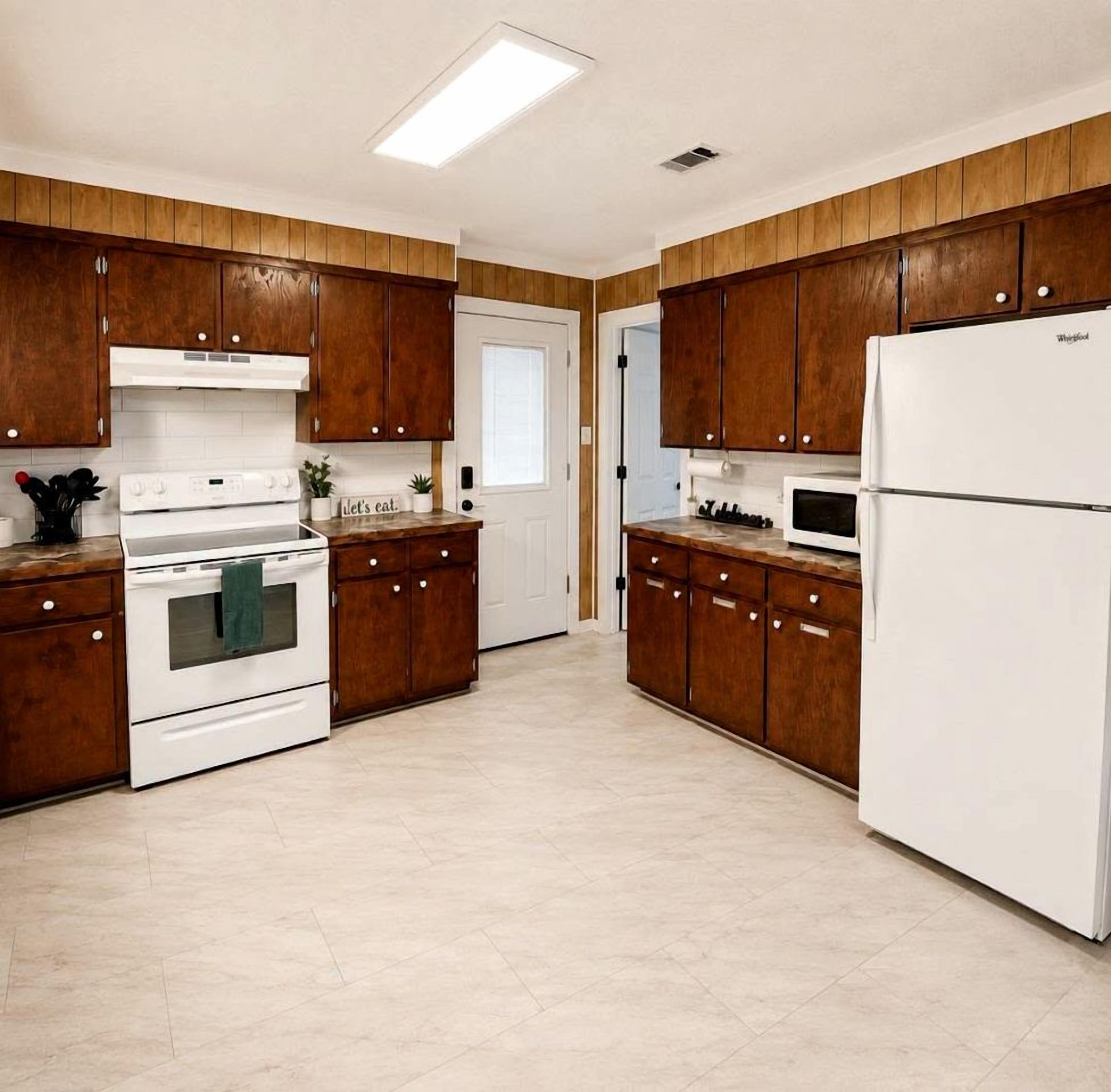 A kitchen with wooden cabinets, a white refrigerator, a microwave, and a stove.