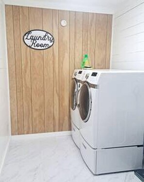 A laundry room with a wooden wall and a washing machine.