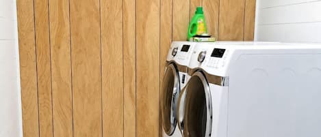 A laundry room with a wooden wall, a washing machine, and a dryer.