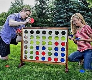 A game board with multiple colored circles, a person holding a red disc, and another person holding a blue disc. - The Gator Den at Caddo Lake in Karnack, Texas (Karnack)