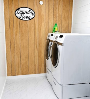 A laundry room with a wooden wall, a washing machine, and a dryer.