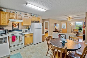 A kitchen with wooden cabinets, a refrigerator, a microwave, and a dining area with a table and chairs.