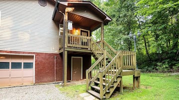 Un bâtiment à deux étages doté d’une terrasse en bois et d’un escalier menant à un balcon.