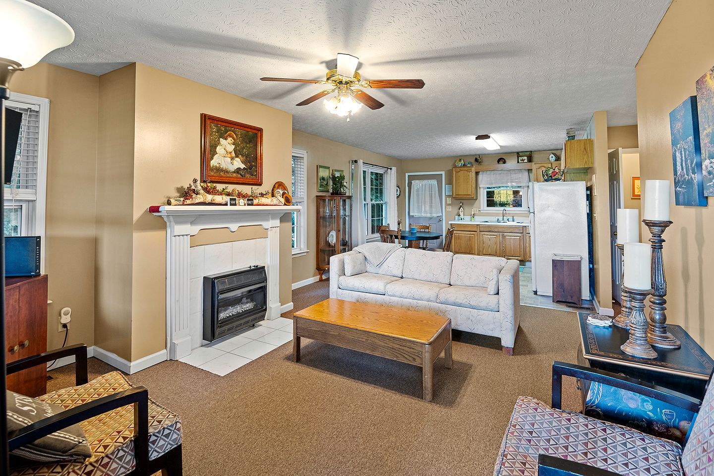 A living room with a fireplace, sofa, coffee table, and a ceiling fan.