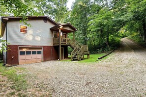 A two-story house with a garage, a wooden deck, and a gravel driveway.