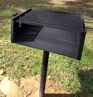 Un barbecue noir pour l’extérieur, doté d’une surface de cuisson plane et d’un compartiment latéral, fixé sur un support en métal.