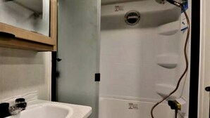 A bathroom with a sink, mirror, and shower enclosure.