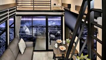 A modern interior with a sofa, dining table, and a staircase.