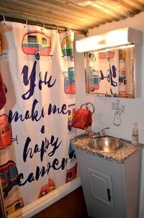 Un baño con cortina de ducha que presenta vehículos coloridos y el texto 'You make me happy'.