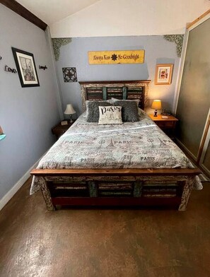 A bed with a Paris-themed bedspread, a pillow with the Eiffel Tower, and a sign above the bed that reads 'Always Kiss Me Goodnight.'