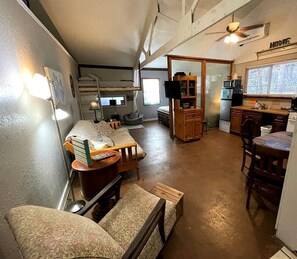 A compact living space with a bunk bed, kitchenette, and a dining area.