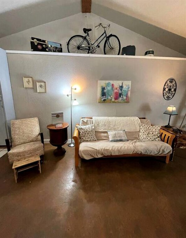 Una sala de estar con sofá, sillón, lámpara y una bicicleta colgada en la pared.