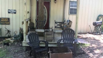A covered porch with two chairs and a table, a red door, and a mailbox indicating private property.