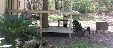 A covered outdoor seating area with a bench, a table, and a chair.