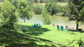 A grassy area with picnic tables and chairs near a lake.