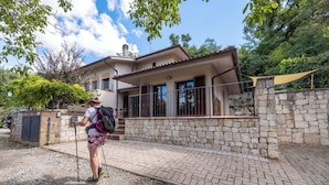 Une maison avec une façade en pierre, un balcon et une entrée pavée.